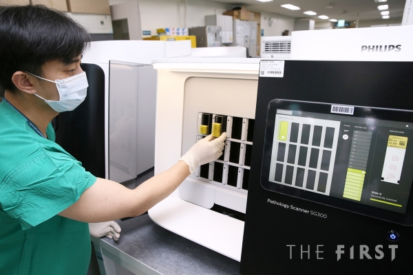 서울아산병원 병리 검사실 직원이 검체 슬라이드를 디지털 스캐너에 넣고 있다